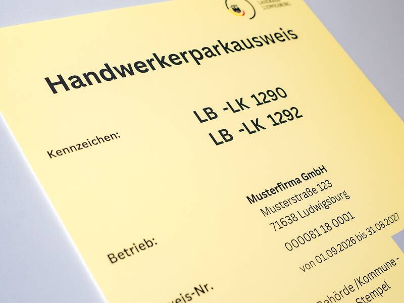 Das Bild zeigt einen gelben Handwerkerparkausweis mit Kennzeichen- und Betriebsinformation, ausgestellt von einer Musterfirma.