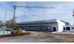 Ein großes, modernes Gebäude im Bau mit einem Gerüst und einem Kran im Hintergrund.