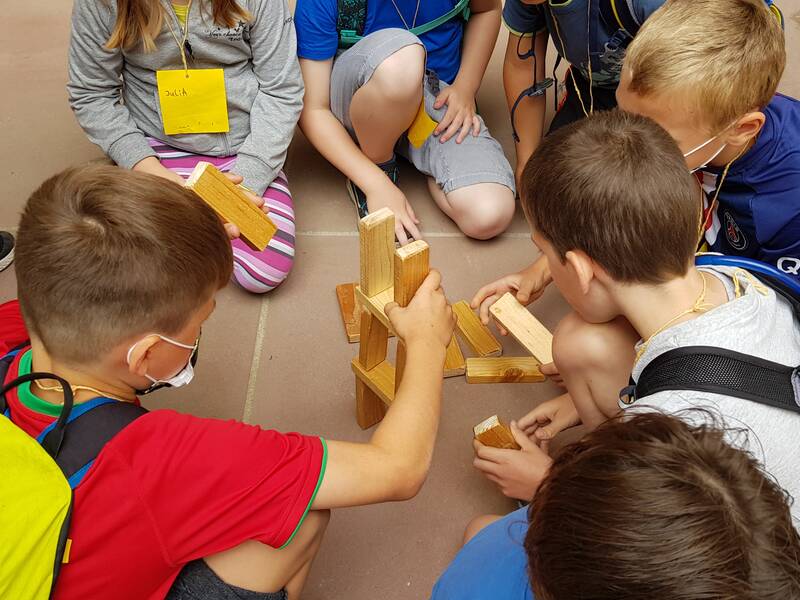 Eine Gruppe von Kindern sitzt auf dem Boden und baut gemeinsam mit Holzklötzen.