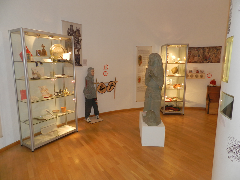 Innenansicht des Stadtmuseums, im Vordergrund steht eine Steinstatue, im Hintergrund zwei Glasschaukasten