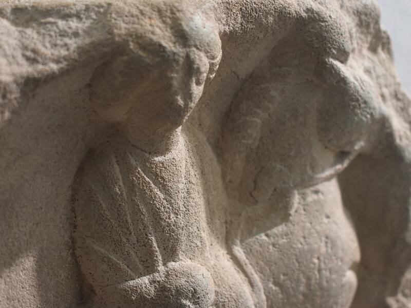 Relief Göttin Epona / Die Abbildung zeigt eine detaillierte Steinreliefskulptur von zwei eng zusammenstehenden Figuren mit fließenden Gewändern.