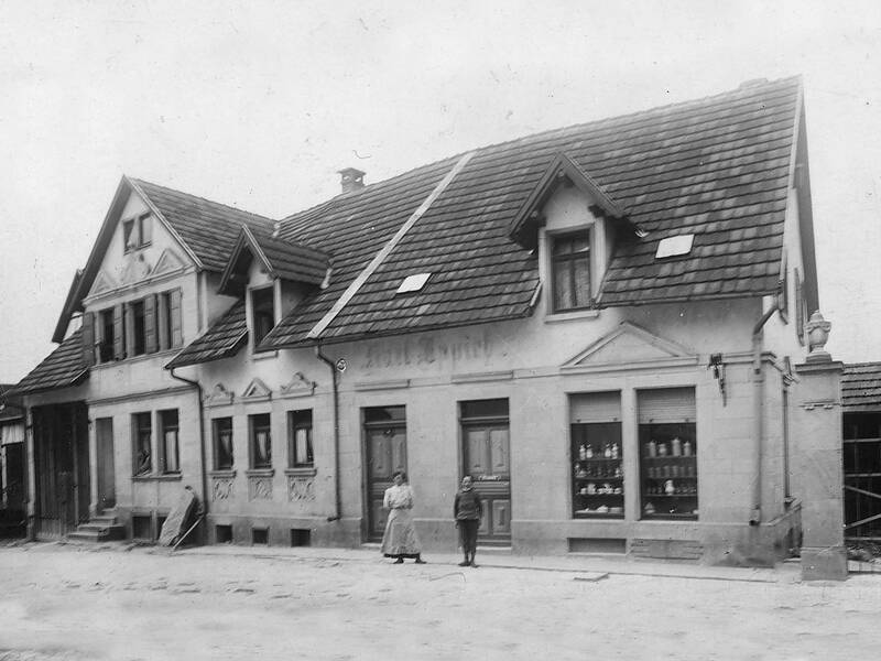 Ein historisches Gebäude mit Schaufenstern und zwei Personen, die vor dem Eingang stehen.