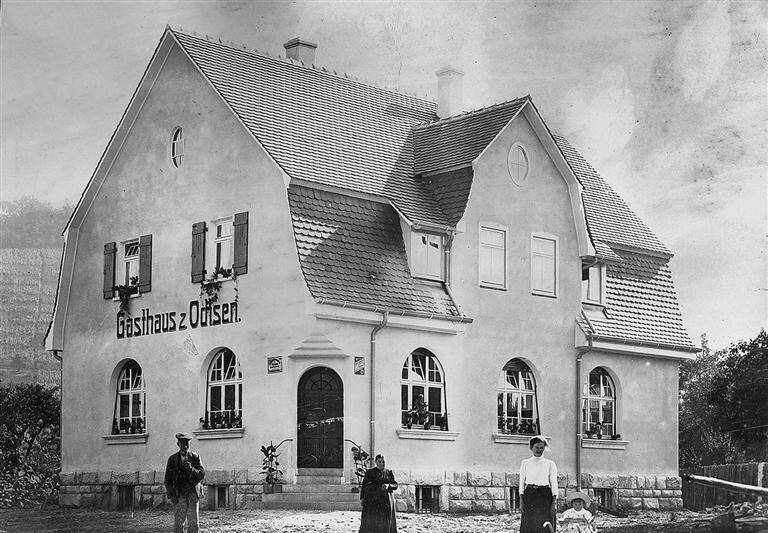 Ein historisches Gebäude mit der Beschriftung "Gasthaus z. Ochsen" und Menschen, die davor stehen.