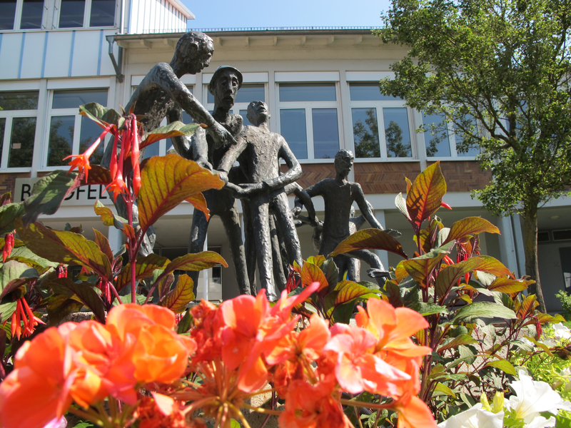 Siebenschwabenbrunnen vor der Burgfeldschule umgeben von Blumen