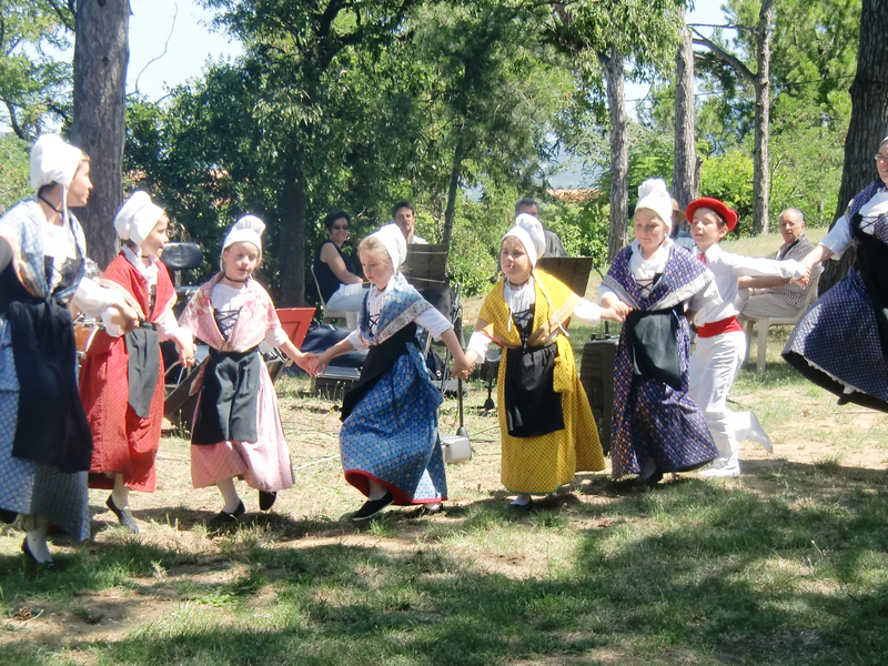 Eine Gruppe von Menschen in traditioneller Kleidung tanzt Hand in Hand im Freien.