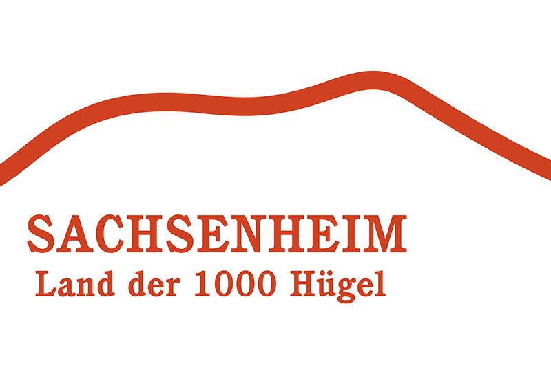 Das Bild zeigt ein Logo mit einer geschwungenen roten Linie über dem Text "Sachsenheim - Land der 1000 Hügel".