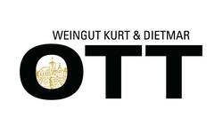 Das Bild zeigt das Logo des Weinguts Kurt & Dietmar Ott mit großen schwarzen Buchstaben "OTT," wobei in dem "O" eine goldene Illustration von Häusern und einem Turm integriert ist.