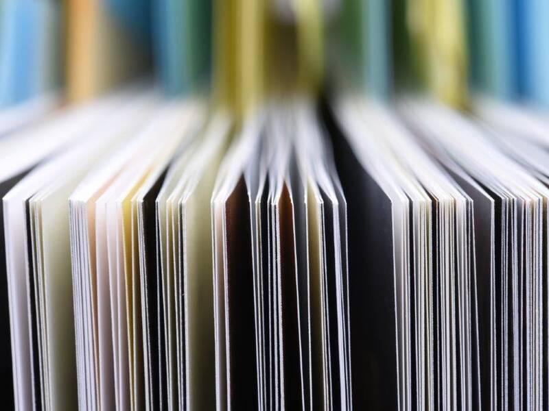 Nahaufnahme von aufrecht stehenden farbigen Buchkanten und Seiten, die eine wellenförmige Anordnung bilden.
