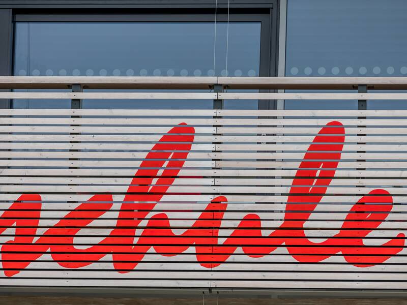 Ein Zaun vor einem Gebäude ist mit dem Wort "schule" in großer roter Schrift bemalt.