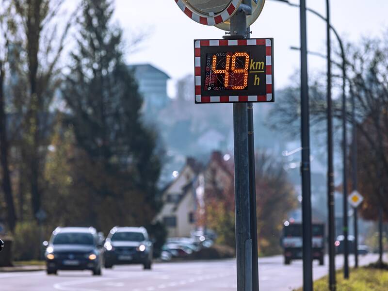 Eine Geschwindigkeitsanzeige, die eine Geschwindigkeit von 49 km/h anzeigt und an einem Laternenpfosten befestigt ist.