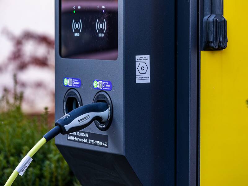 Nahaufnahme einer E-Ladestation mit einem eingesteckten Ladekabel.