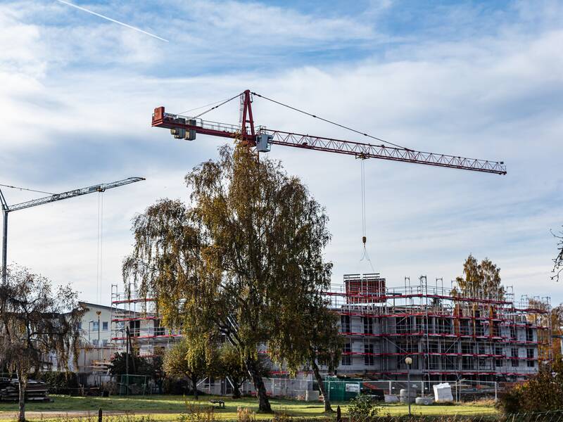 Zwei gelbe Baukräne bei einer Baustelle für ein Haus.